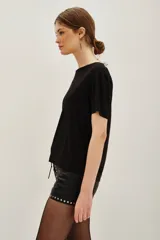 Remera negra de manga corta con cuello redondo, decorada con pequeñas aplicaciones brillantes dispersas en la parte frontal y mangas.