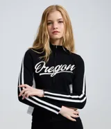 Campera deportiva de fleece color negro con cuello alto y cierre frontal. Presenta el lettering 'Oregon' bordado en el pecho y rayas blancas contrastantes a lo largo de las mangas.