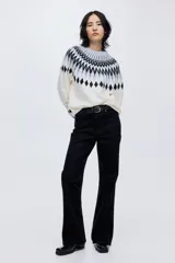 Buzo de punto jacquard con diseño de patrón geométrico en cuello y puños, corte oversized, cuello redondo y mangas raglán con terminaciones acanaladas.