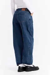 Jean de corte balloon con tiro alto y silueta amplia que se estrecha ligeramente hacia el tobillo. Presenta un diseño de cinco bolsillos, cierre frontal con botón y bragueta, y costuras reforzadas.