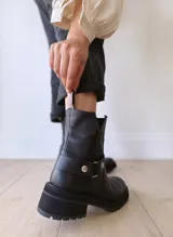 Bota corta negra de cuero, con caña media, hebilla lateral y suela track.