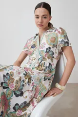 Vestido camisero largo de corte recto, con estampado de arabescos en tonos verde agua, rosa, marrón y gris. Tiene cuello camisero, mangas cortas y cierre frontal con botones.