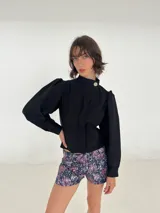 Campera de bengalina con cierre frontal, cuello alto con botón y mangas largas abullonadas con puños abotonados.