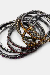 Pack de pulseras elásticas múltiples con estructura metálica oscura y aplicación de cristales en tonos ámbar y violeta.