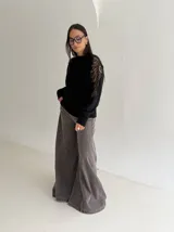 Sweater negro de tejido de punto con cuello redondo y mangas largas. Presenta detalles de transparencias y apliques bordados con pedrería en la parte superior de las mangas.