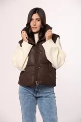 Chaleco acolchado de nylon color marrón, con cuello alto, cierre frontal de cremallera y botones a presión.