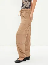 Pantalon cargo color tostado con cintura elastizada y cordón ajustable. Presenta bolsillos laterales tipo cargo y costuras visibles a lo largo de las piernas.