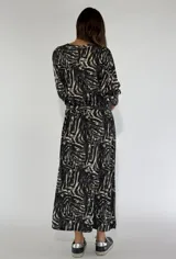 Vestido largo azul con estampado abstracto en blanco y negro, corte recto y mangas largas abullonadas.
