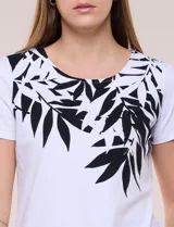 Remera de silueta recta confeccionada en algodón y elastano, de color blanco. Presenta escote redondo, mangas cortas, ruedo recto con tajos laterales y un diseño destacado en la pechera con aplique de piedras a tono.
