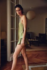 Shorts de tiro alto confeccionado en tejido satinado color verde oliva, con cintura elástica, bajo con volantes y aberturas laterales decoradas con aplicaciones de encaje a tono.