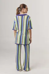 Pantalón largo de tejido crochet con rayas verticales en tonos azul, verde, marrón y blanco.