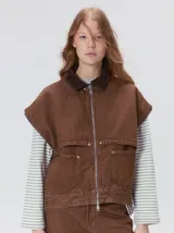 Campera de denim a rayas verticales con cuello de pana en color bordó. Presenta cierre frontal, mangas desmontables con cierre en los hombros, canesú en el pecho y bolsillos de parche cuadrados.