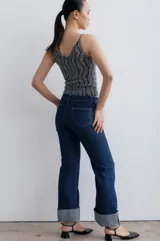 Jean de mezclilla azul oscuro con costuras contrastantes marcadas en el frente y dobladillo ancho vuelto en el ruedo.