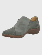 Zapato casual Hush Puppies modelo Albi, confeccionado en cuero gris con perforaciones decorativas en toda la superficie. Presenta un diseño de empeine cerrado con ajuste lateral de velcro y suela de goma en color marrón.