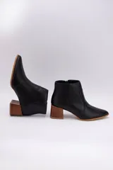 Botas cortas de cuero color beige, con punta fina y cierre lateral. Tienen un taco cuadrado de madera.