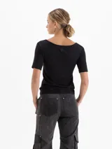 Remera negra de poliamida con elastano, de calce ajustado, con escote redondo amplio y mangas cortas al codo.