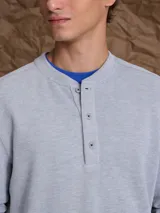 Buzo de tejido rib color azul marino, con cuello redondo a la base y cierre frontal parcial con botones. Presenta mangas largas con puños ajustados y diseño de calce holgado.