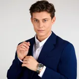 Reloj analógico Maserati modelo Successo con caja y brazalete de acero inoxidable. Presenta una esfera gris con efecto cepillado, índices plateados, ventana de fecha y segundero en color naranja.