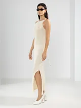 Vestido largo tejido color crudo, con cuello halter, espalda baja y abertura lateral.