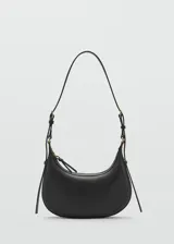 Riñonera de diseño minimalista en color negro, confeccionada en material efecto piel con acabado liso. Presenta una forma curva estructurada, cierre superior con cremallera y una correa ajustable con hebilla metálica que permite llevarla al hombro o cruzada.