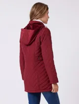 Campera capitoneada de largo midi en color bordó, con diseño de rombos en el cuerpo y mangas, y costuras diagonales en los laterales. Cuenta con cierre frontal, capucha desmontable con interior suave y panel entallado en la cintura.