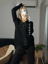 Sweater de punto color bordó con escote en V y detalle de strass aplicado en la parte frontal. Presenta mangas largas y corte holgado.