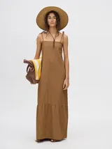 Vestido midi de denim color marrón, con corte holgado, breteles finos con lazos ajustables y detalle de volado en el ruedo.