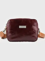 Morral rectangular de cuero color bordó con acabado brillante. Presenta una placa metálica con el nombre "Tranquera" en el frente. Incluye una correa ancha de cuero color camel con costuras decorativas, ajustable y desmontable mediante ganchos metálicos.