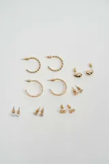 Set de aros variados en tono dorado, que incluye aros tipo argolla trenzados, argollas lisas, aros tipo gota, aros con piedras brillantes, aros con perlas y aros con diseño floral.