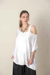 Blusa blanca italiana lisa, de corte irregular con un hombro descubierto y calce holgado.