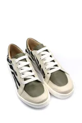Zapatillas deportivas bajas de cuero con estampado de cebra en blanco y negro, detalles en verde oliva y cordones blancos.