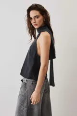 Blusa crop azul oscuro con cuello alto y diseño sin mangas, de tela con caída suave y ligero brillo.