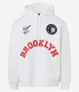 Hoodie blanco con capucha y cordones ajustables, confeccionado en algodón con felpa interior. Presenta estampado frontal con la palabra 'BROOKLYN' en color rojo, un parche circular con la imagen de Notorious B.I.G. y una firma bordada. Cuenta con bolsillo canguro y puños ajustados.