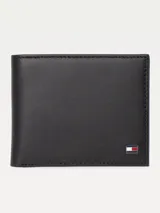 Billetera plegable de cuero negro liso con forro estampado a rayas. Incluye múltiples ranuras para tarjetas y billetes, y logo pequeño de Tommy Hilfiger en la parte inferior.