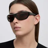 Lentes de sol envolventes con montura negra de diseño oversize y cristales color marrón. Presentan una silueta inspirada en los años 2000 con protección UV400.