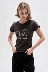Remera de algodón color marrón oscuro, de manga corta y corte ajustado al cuerpo, con cuello redondo a la base y detalle de bordado con tachas formando el número 14 en el frente.