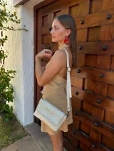 Cartera bandolera de cuero con solapa frontal texturizada en efecto cocodrilo metalizado color dorado. Cuenta con correa larga ajustable y desmontable, cierre principal y forro interno de tela.