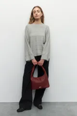 Sweater de tejido de punto color gris melange, con cuello redondo y diseño de franjas horizontales en relieve. Presenta mangas largas acampanadas y un corte holgado.