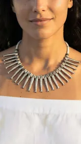 Collar dorado con dijes en forma de peces y cuentas blancas.