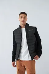 Campera negra con cuerpo acolchado de nylon y mangas de felpa. Tiene cuello alto, cierre frontal, bolsillos laterales con cierre, logo estampado en el pecho y logo de goma en la manga.