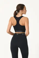 Top deportivo negro con logo blanco en el frente y banda elástica con letras grises en el bajo busto.