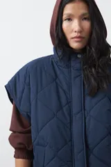 Chaleco acolchado de nylon con diseño capitoneado, cuello alto y cierre frontal con botones a presión. Presenta un calce amplio y versátil.