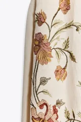Vestido corto color crudo con tirantes finos ajustables, escote recto y bordado floral a contraste.