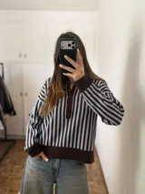 Sweater de punto con diseño de rayas verticales en tonos celeste y marrón, manga larga, cuello polo con solapa y botones frontales, y puños y ruedo elásticos de tejido rib.