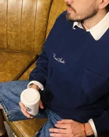 Buzo azul marino de corte clásico con cuello redondo, puños y cintura acanalados. Presenta un bolsillo cuadrado en el pecho y logo de la marca bordado en blanco.