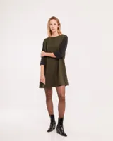 Vestido corto negro con mangas 3/4 verdes, cuello bote y bolsillos laterales.