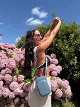 Bandolera compacta color rojo con textura de cuero, correa regulable y desmontable con diseño de rayas rojas y blancas. Cuenta con bolsillos frontales y cierre, interior forrado en tela.