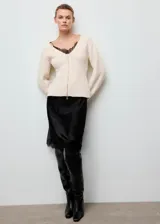 Chaqueta de punto de diseño entallado con cuello en pico y cierre frontal mediante cremallera. Presenta manga larga y un tejido de punto medio.