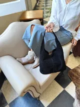 Bolso tipo tote bag negro de cuero, con costuras a la vista y manijas cortas.