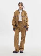Pantalón jean de tiro alto y corte pinzado, con perneras de caída suelta y levemente anchas en el bajo. Posee pasador con hebilla en la parte trasera.